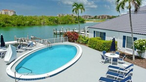 A swimming pool with lounge chairs and a view of the water. - Dolphin Paradise- Peaceful 1-bedroom condo in historic Old Marco Island (Marco Island)