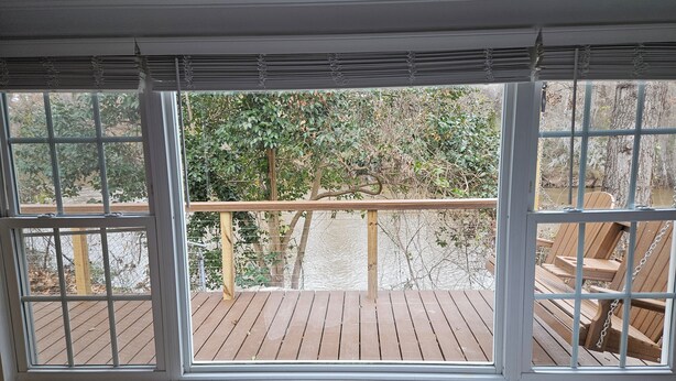 Un dormitorio con un ventanal que da a una terraza de madera y un río.