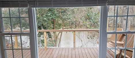 Un dormitorio con un ventanal que da a una terraza de madera y un río.
