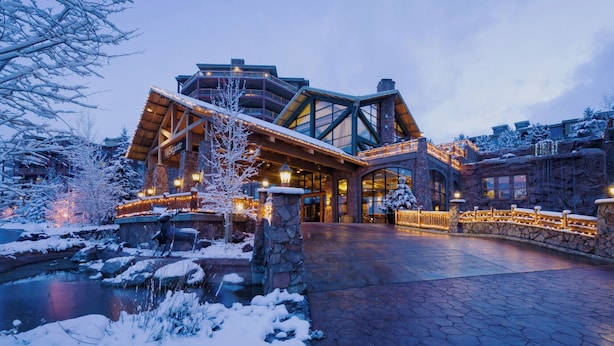 A lodge with a stone facade, large windows, and a covered outdoor area with a snow-covered landscape. - Park City, Ski-in, Ski-out, 2-bed 2 bath, Sleeps 8 (Park City)