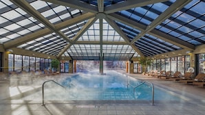 An indoor swimming pool with a glass ceiling, lounge chairs, and a visible steam feature. - Park City, Ski-in, Ski-out, 2-bed 2 bath, Sleeps 8 (Park City)