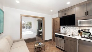 A compact kitchen with modern appliances, a dining area with a sofa, and a view through an open door to a balcony. - Park City, Ski-in, Ski-out, 2-bed 2 bath, Sleeps 8 (Park City)