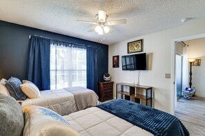 Ein Schlafzimmer mit zwei Betten, einem Deckenventilator, einem Fernseher und einer Kommode.