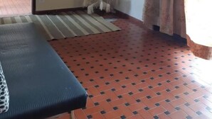 A room with a ceiling fan, a bench, a patterned rug, a wall-mounted air conditioner, and a window with curtains. - Simple house near Praia Sonho - Itanhaém (family/small groups) (Itanhaém)