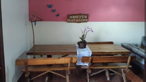 A dining area with wooden tables and benches, a ceiling fan, a wall-mounted sign, and a potted plant. - Simple house near Praia Sonho - Itanhaém (family/small groups) (Itanhaém)
