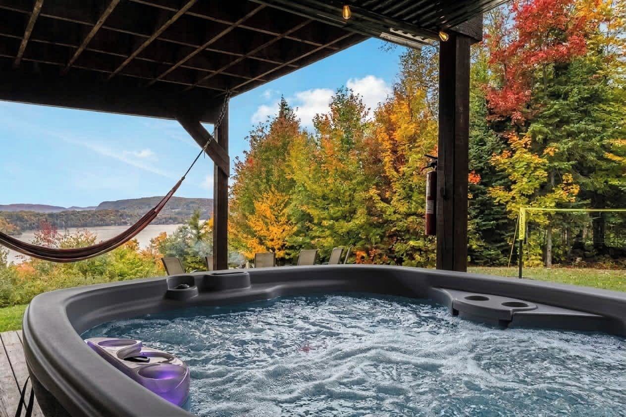 Un jacuzzi con vistas a árboles otoñales y un paisaje lejano.
