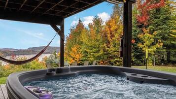 Un jacuzzi con vistas a árboles otoñales y un paisaje lejano.