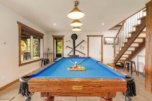 A pool table with a nameplate, a staircase, and a window with a view of trees. - Spa, Pool table & River | Hauteur du Saint-Maurice (Grandes-Piles)