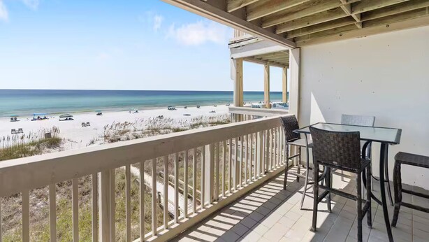 Un balcon avec vue sur la plage, une table et des chaises.