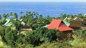Un complejo turístico costero con varias edificaciones tipo bungalow, cada una con techo rojo, rodeadas de exuberante vegetación y palmeras.