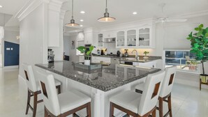 A spacious kitchen with granite countertops, white cabinetry, and a central island with bar stools. - Private Pier & Pool / 5 min to Kemah Boardwalk (Kemah)
