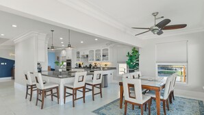 A spacious kitchen with white cabinets, a central island, and a dining area with chairs and a table. - Private Pier & Pool / 5 min to Kemah Boardwalk (Kemah)
