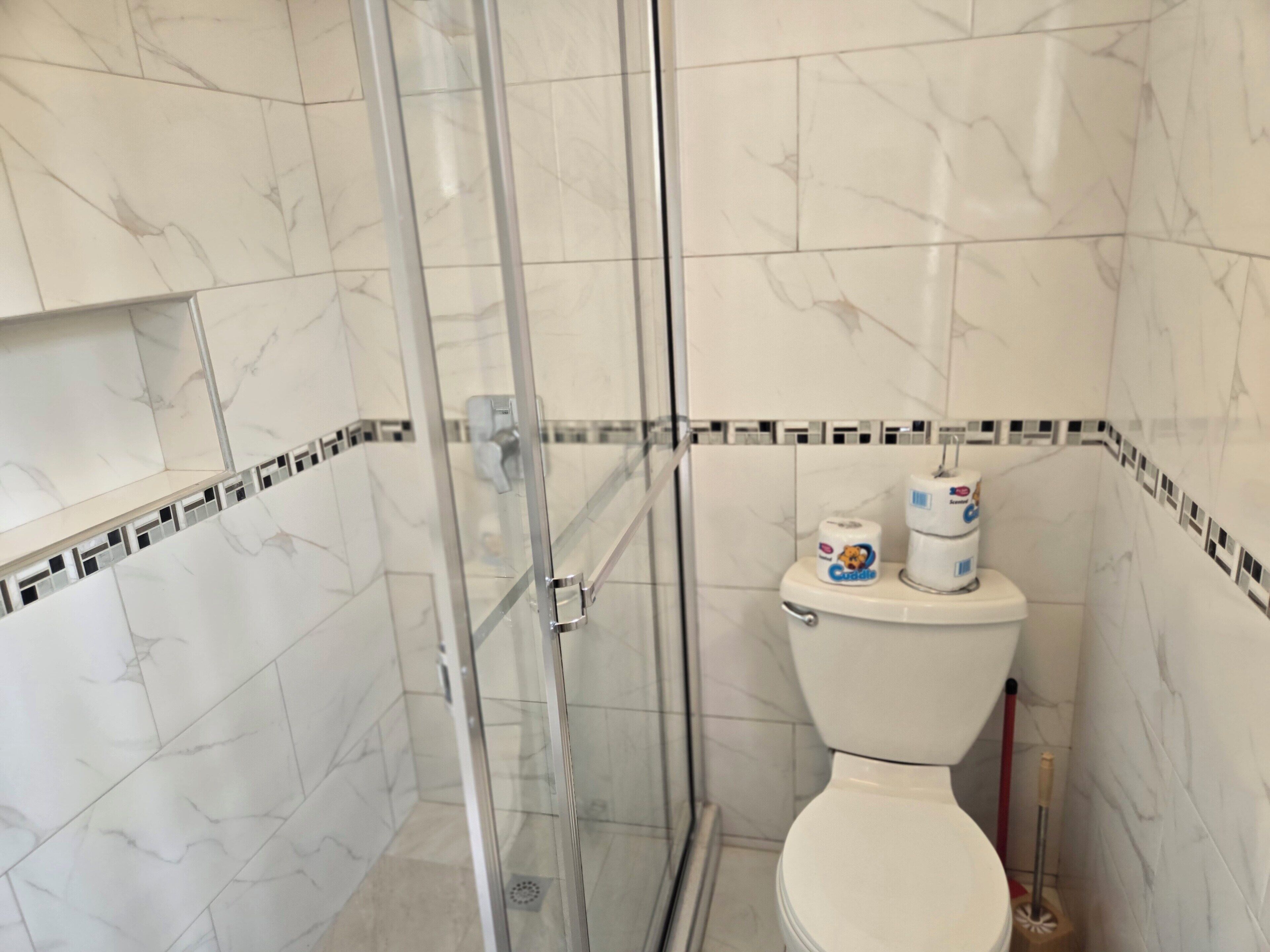 Une salle de bain avec une douche à parois de verre, des toilettes et un bidet.
