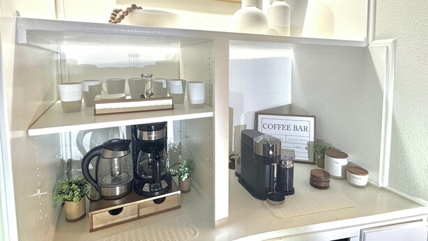 Un coin cuisine aménagé en espace «
bar à café
», comprenant une machine à café, des tasses et un panneau indiquant
: «
BAR À CAFÉ
».