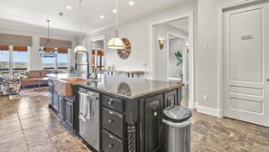 A spacious kitchen with a large island, pendant lighting, and a view to the outside.