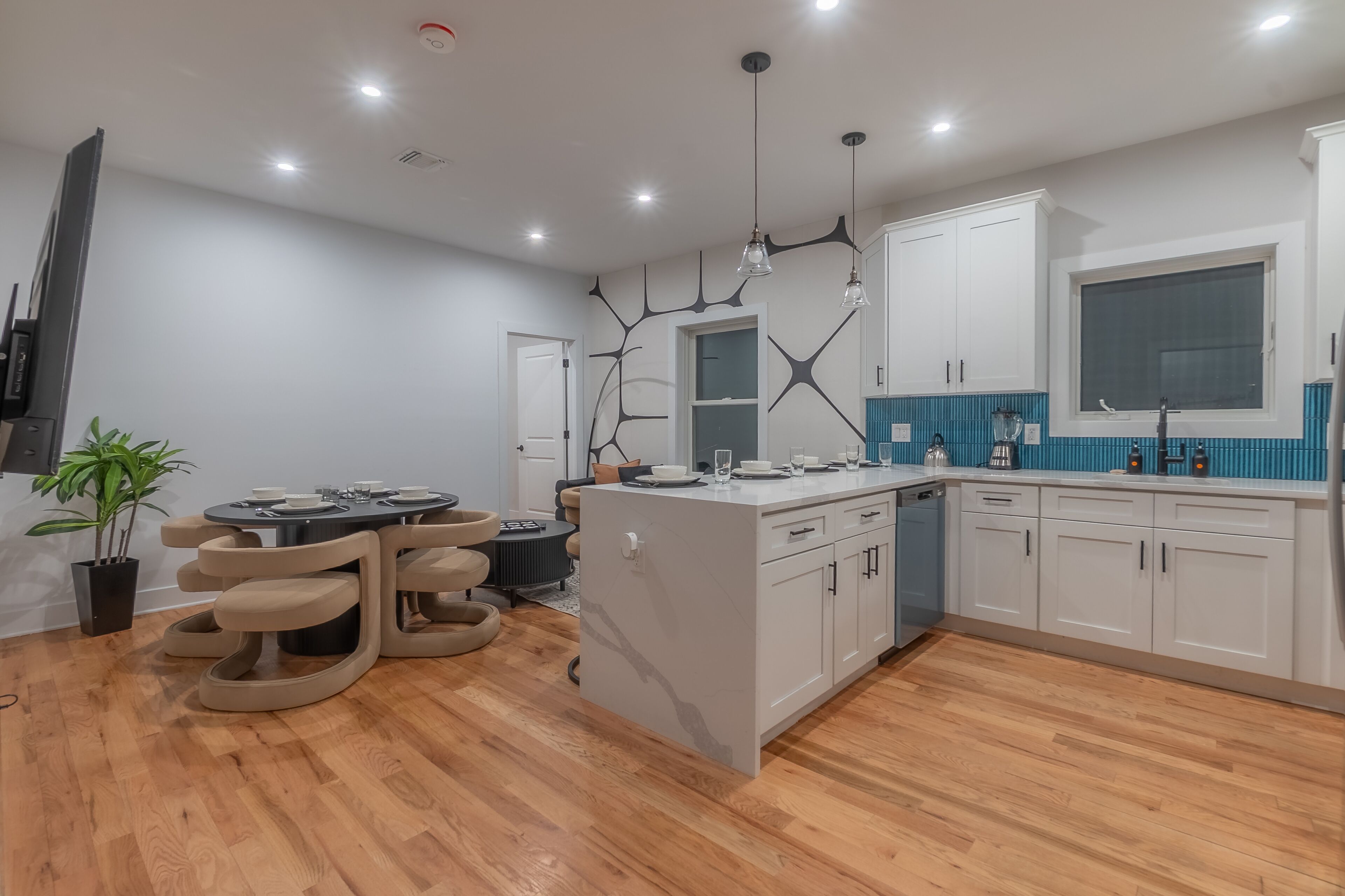 A modern kitchen with a central island, white cabinets, and a blue backsplash.