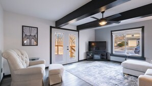 A modern living room with a large TV, comfortable seating, and a view of the outside. - 3-bedroom house in peaceful Creve Coeur private fenced yard minutes from Peoria  (Creve Coeur)