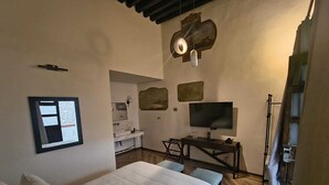 Una camera da letto con un letto, una scrivania con televisore, uno specchio e opere d'arte alle pareti.