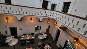 Un ristorante con posti a sedere all'aperto, pareti bianche e illuminazione decorativa.
