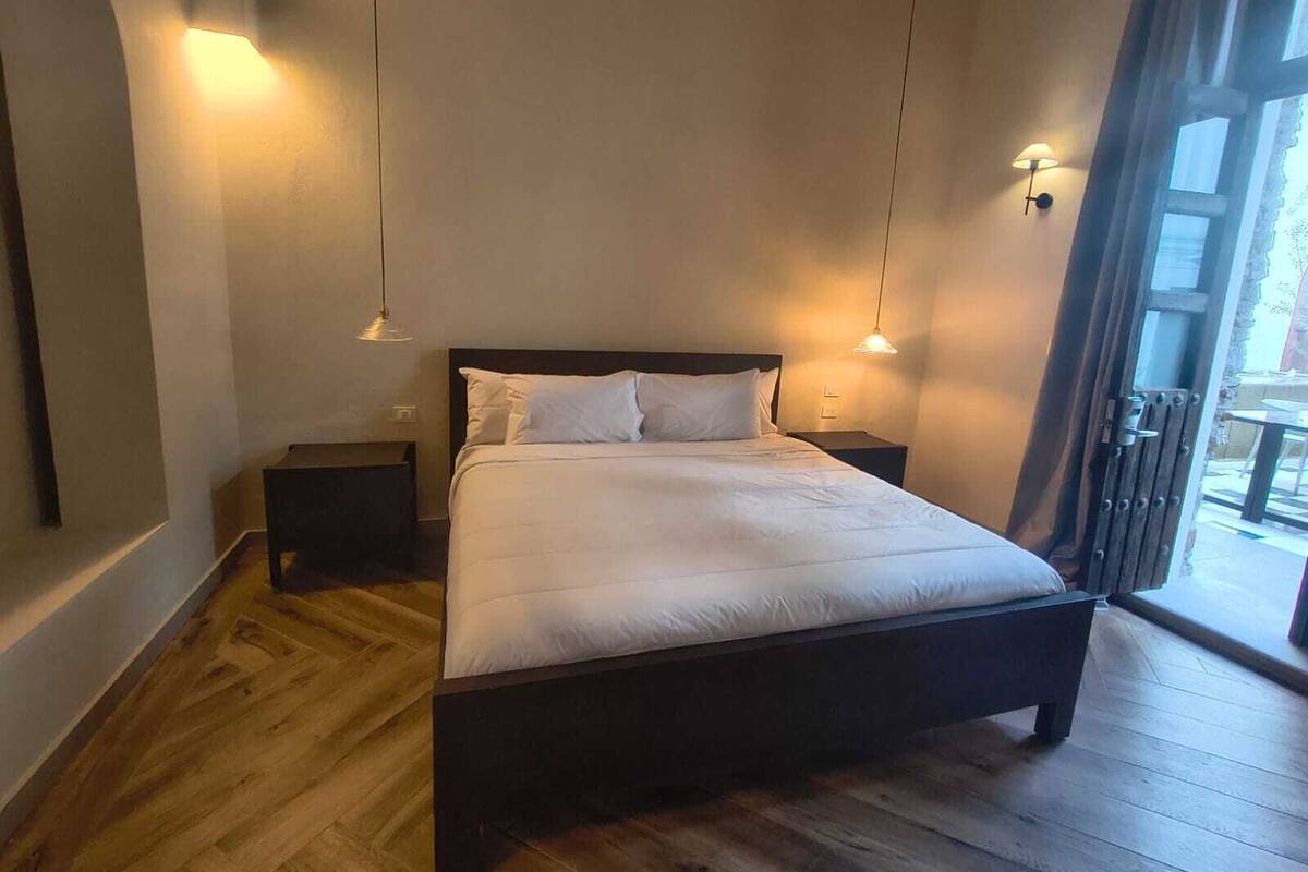 Ein Schlafzimmer mit Holzboden, einem Bett mit weißer Bettwäsche, zwei Nachttischen und Wandleuchten.