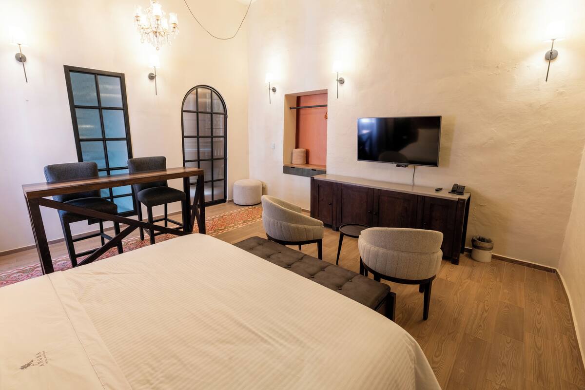 Ein Hotelzimmer mit einem Bett, einem Schreibtisch mit zwei Stühlen, einem Fernseher und einem Schrank.