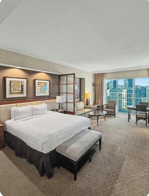 Una habitación de hotel con una cama grande, un escritorio, una silla y vistas a la ciudad.