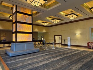 A hotel lobby with a reception desk, a seating area, and a large decorative column. - AWESOME ONE BEDROOM HIGH RISE PENTHOUSE WITH BALCONY, AMAZING STRIP VIEW !! (Las Vegas)