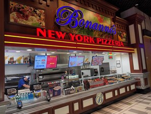 A pizzeria with a neon sign, a menu board, and a self-service beverage station. - AWESOME ONE BEDROOM HIGH RISE PENTHOUSE WITH BALCONY, AMAZING STRIP VIEW !! (Las Vegas)