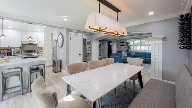 Eine moderne Küche mit integrierten Geräten, ein Essbereich mit einem Marmortisch und ein Wohnzimmer mit einem blauen Sofa.