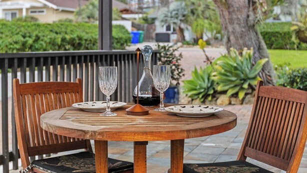 A wooden table with two chairs, a bottle, and two glasses on a patio. - Stylish Two Bedroom House in Peaceful Neighborhood (Carlsbad)