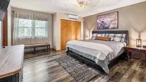 A bedroom with a bed, a bench, a desk, and a ceiling fan.