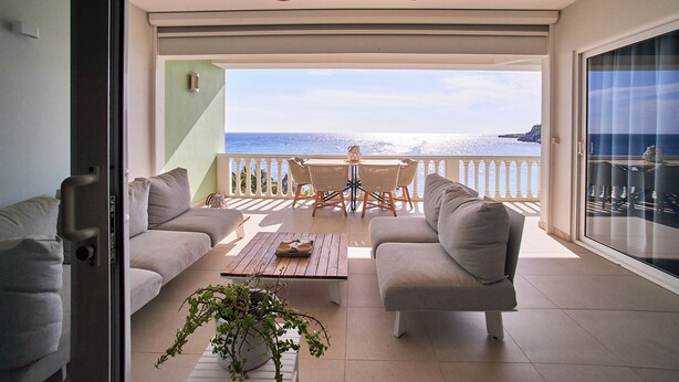 A balcony with a sofa, a table, and a potted plant. - 2-bedroom apartment in Blue Bay Resort (Willemstad)