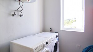 A laundry room with a washing machine and dryer, a water heater, and a window providing natural light. - 2-bedroom apartment in Blue Bay Resort (Willemstad)