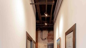 Un pasillo con piso de madera, paredes blancas y una puerta al final.