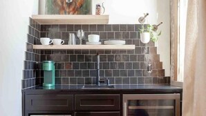 Una cocina con microondas, cafetera y un armario de vidrio.