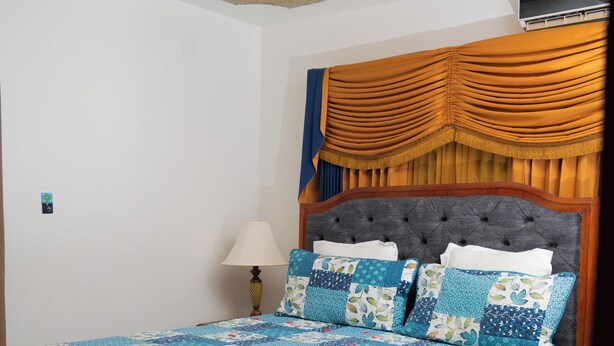 A bedroom with a bed, a nightstand, a lamp, and a ceiling fan. - The Hideaway (St. Ann Parish)