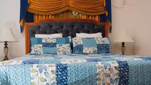 A bedroom with a large bed, a headboard, and a television mounted on the wall. - The Hideaway (St. Ann Parish)