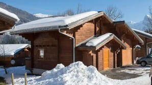 A wooden cabin with a sloped roof, surrounded by snow, set against a mountainous backdrop. - Eden Criou - Chalet sleeps 7 to 9 - pool/sauna (Morillon)