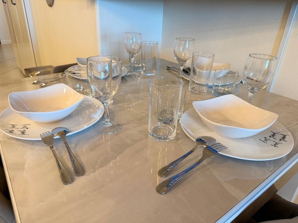 A dining table set with white plates, clear glassware, and silverware. - Las Palomas 1BR 1BA Luxury Ocean View (Puerto Penasco)