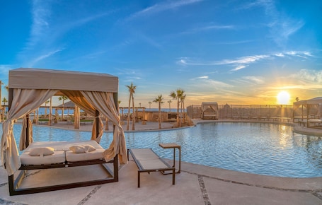 A poolside area with a canopy bed and lounge chairs.