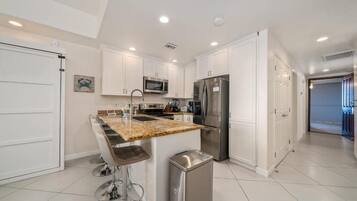 A modern kitchen with white cabinets, stainless steel appliances, and a granite countertop.