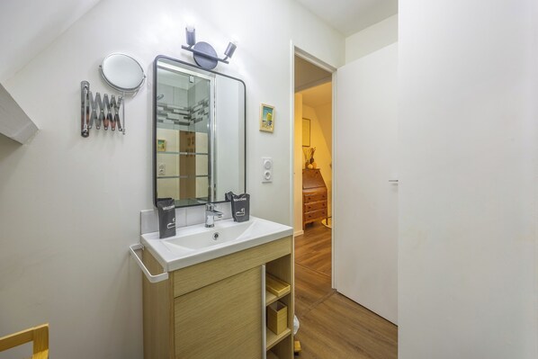 Un bagno moderno con un lavandino bianco, uno specchio grande e un porta asciugamani.
