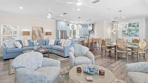 Ein modernes Wohnzimmer mit Ecksofa, rundem Couchtisch und Essbereich mit Stühlen.