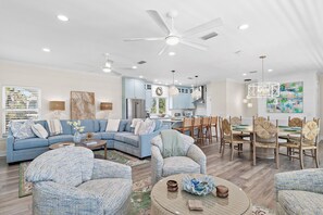 A modern living room with a sectional sofa, round coffee table, and dining area with chairs. - 391 BLUE MOUNTAIN RD ...4 Bedrooms w/ Private Pool... STEPS TO THE BEACH! (Santa Rosa Beach)