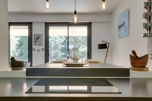 Una cucina moderna con isola centrale, illuminazione a sospensione e vista su piante.