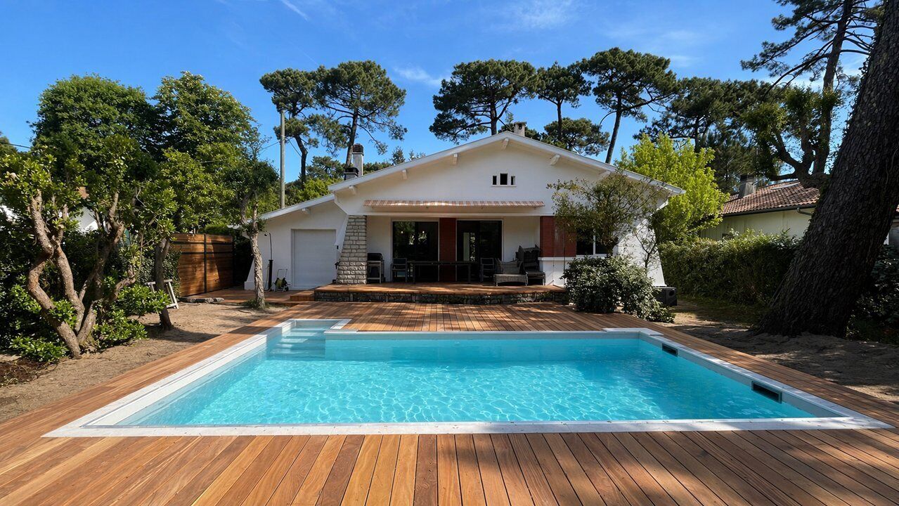 Una casa con piscina, terraza de madera y porche cubierto.