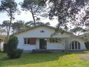 Ett envåningshus med ett sadeltak, en veranda och en liten trädgård framför huset.