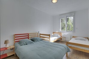 Ett sovrum med två enkelsängar, ett nattduksbord med en lampa och ett fönster som släpper in naturligt ljus.