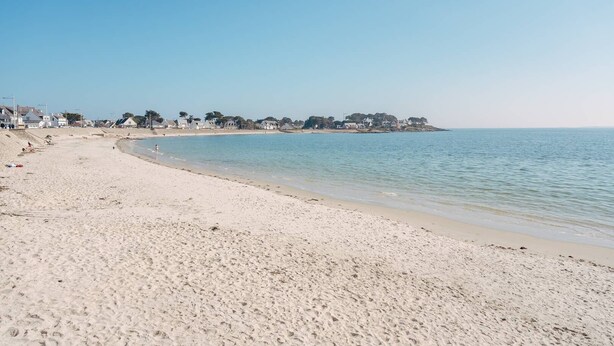 A wide sandy beach with a calm sea, a clear sky, and houses in the background. - Carnac - 3-room apartment - 50m² - Wifi - Pool (CARNAC)