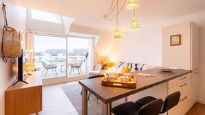A modern kitchen with a central island, pendant lights, and a view to an outdoor seating area. - Carnac - 3-room apartment - 50m² - Wifi - Pool (CARNAC)